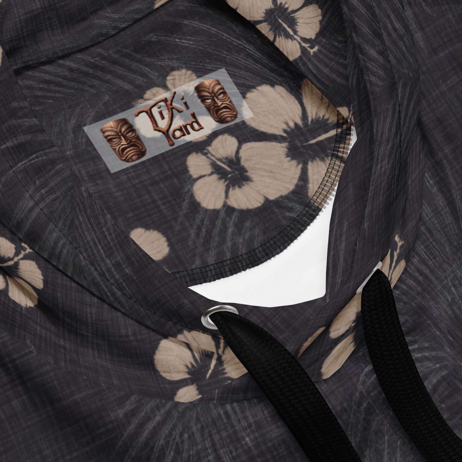 Close-up of a black Hawaiian hoodie with floral pattern, showcasing the brand tag and black drawstrings.