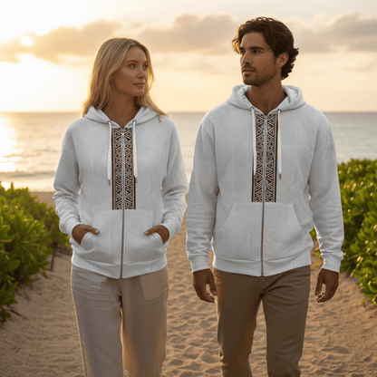 Man and woman wearing matching Islander zip hoodies with geometric tribal pattern walking on resort beach path at sunset