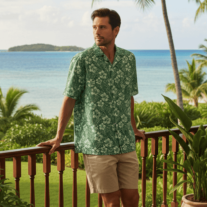 Man wearing Kauwela Verdance Hawaiian shirt on resort lanai with ocean and tropical garden views