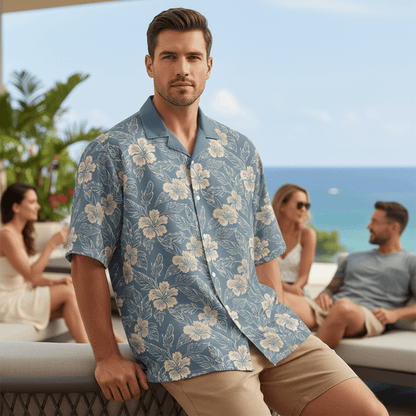 Man wearing Kailua Opus Hawaiian shirt with slate blue base and cream hibiscus flowers casually leaning on modern furniture at upscale resort terrace