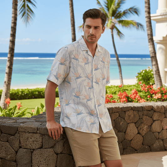 Man wearing Pacific Paradise Hawaiian shirt with delicate birds of paradise flowers leaning against terrace railing at beachfront resort
