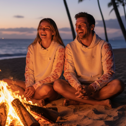 Couple wearing Pacific Sand Hawaiian hoodies by evening beach bonfire in Hawaii