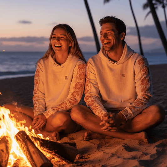 Couple wearing Pacific Sand Hawaiian hoodies by evening beach bonfire in Hawaii
